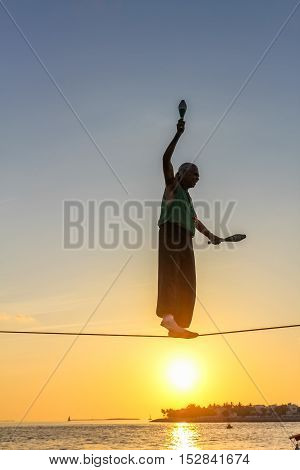 Key West, Florida, United States - April 13, 2012: a tightrope walker tosses of skittles. Show of street artists that takes place every day during the sunset celebration at Mallory Square in Key West.