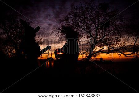 Siluet Halloween witches holding a pumpkin in sunset