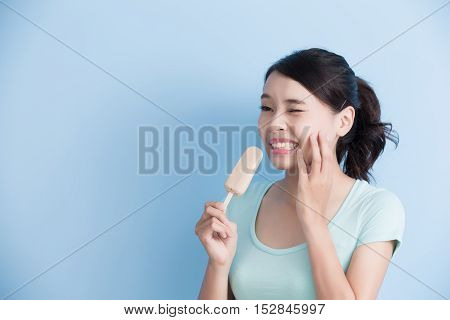 woman have sensitive teeth with ice isolatd on blue background asian