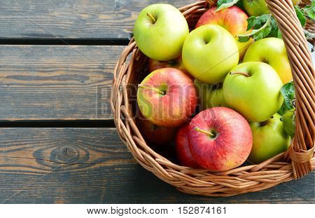 colorful and various kinds of apples in the basket on wooden background