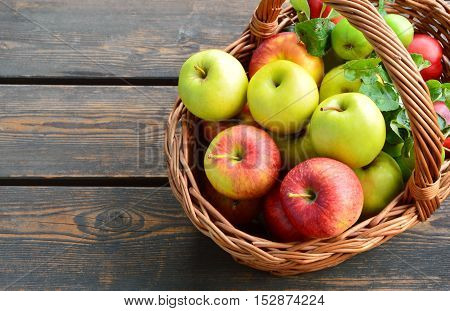 colorful and various kinds of apples in the basket on wooden background