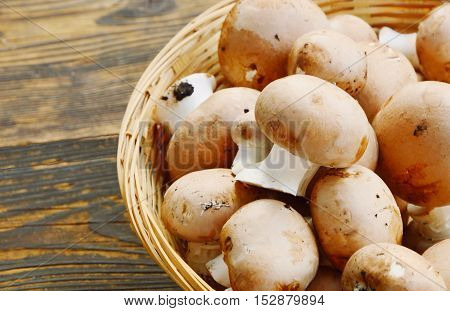 Fresh cremini mushrooms in the basket on wooden floor.