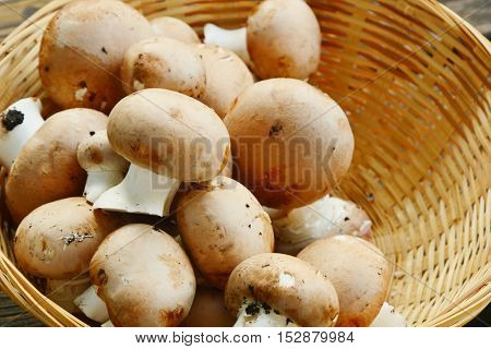 Fresh cremini mushrooms in the basket on wooden floor.