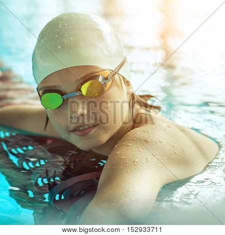 Swimmer child. Portrait of swimming child athlete with goggles after training in waterpool.