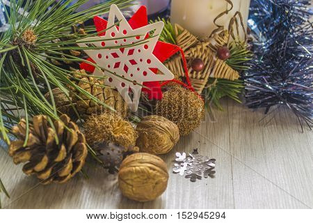 Pine cones with walnuts and candle with christmas decoration on wooden table. Copyspace background.