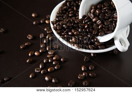 Brown coffee grains in a cup and on a saucer