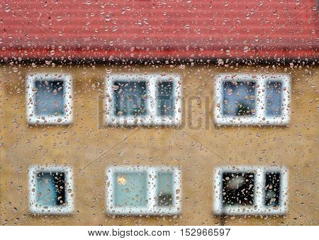 Raindrops on window glass with blurred building as background