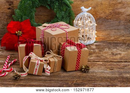 Carton handmade gift boxes on wooden background, poinsetia or christmas red star flower in background