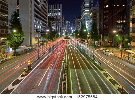 Tokio, Japan - Setember 5, 2016: Car light trails in a busy wide avenue with a tunnel in the middle and illuminated buildings on the background.