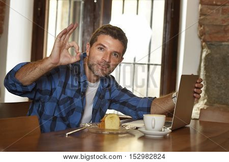 young attractive businessman or student on his 30s wearing casual clothes working or studying with laptop computer at coffee shop drinking tea cup and cake in modern business self employed concept