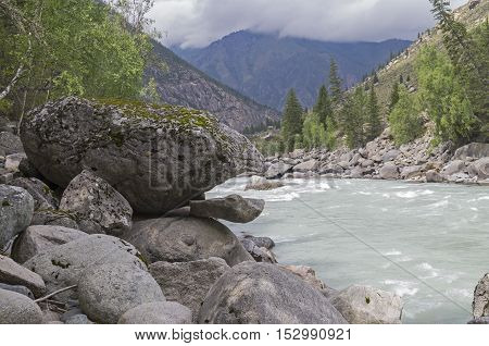 Bizarre stone on the shore of a mountain river. Rapids 
