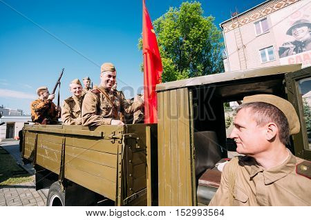 Gomel, Belarus  - May 9, 2016: Group Of Men Sitting In Russian Soviet Military Truck ZIS-5V In Soldiers Uniform With Weapon Of WW2 Time And Victory Red Flag. Preparing For The 9th May Victory Parade
