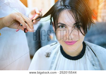 Beauty, hairstyle, treatment, hair care concept, young woman and hairdresser cutting hair at hairdressing salon. Hairdresser cuts happy girl's hair. Hairstylist serving client at barber shop