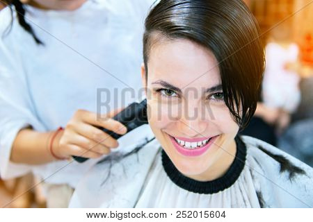 Beauty, hairstyle, treatment, hair care concept, young woman and hairdresser cutting hair at hairdressing salon. Hairdresser cuts happy girl's hair. Hairstylist serving client at barber shop