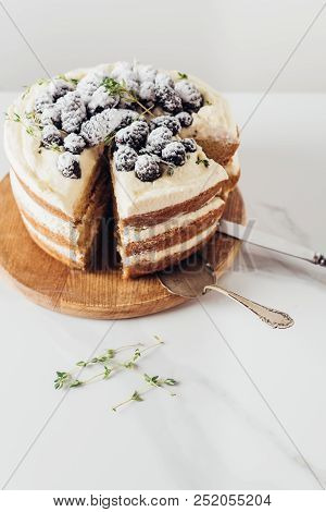 Close-up Shot Of Freshly Baked Sliced Blackberry Cake On Wooden Cutting Board With Cake Server