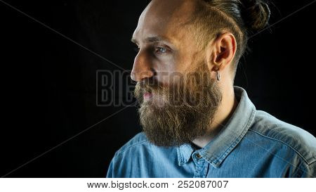 Portrait Of Bearded Man In A Blue Denim Shirt On Black Background.