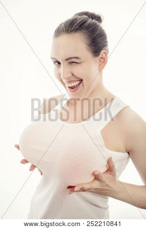 Young Woman Shows Her Big Fake Breasts On White Background Looking At Camera Screaming