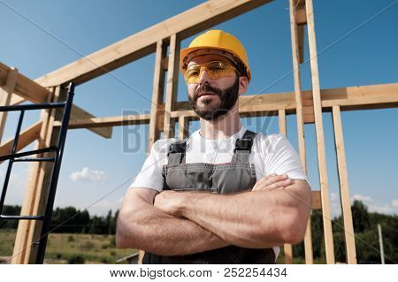 The Man Is A Builder On The Roof Of A Wooden Frame House.