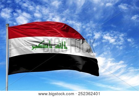 National Flag Of Iraq On A Flagpole In Front Of Blue Sky