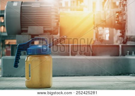 Lubricant Bottle On Floor With Blurred Machinery Industrial Background, Oil Lubrication In Factory C