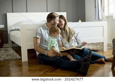 Parents Reading Book To Little Boy And Have Fun On The Floot In The Room