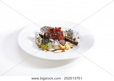 Close-up portrait of exquisite meal. Delicious beef cheeks with grilled vegetables and parsnip puree. Colourful diet dish. Isolated on white background