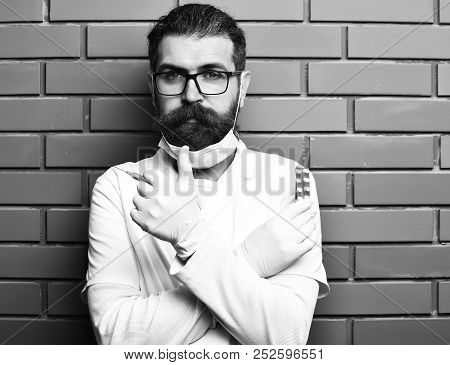 Postgraduate Student In Medical Gown, Gloves Holding Syringe And Pills On Brown Brick Wall Studio Ba