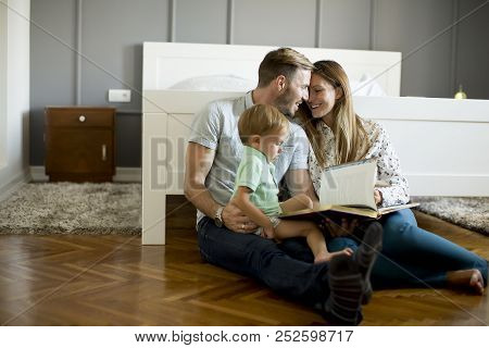 Parents Reading Book To Little Boy And Have Fun On The Floot In The Room