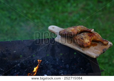 Grilled Hot Grilled Chicken Thighs On A Grill On A Wooden Board With Smoke Around. Outdoors. Free Sp