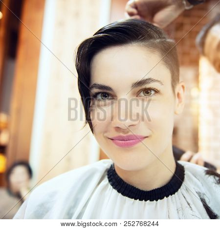 Beauty, hairstyle, treatment, hair care concept, young woman and hairdresser cutting hair at hairdressing salon. Hairdresser cuts beautiful girl's hair. Hairstylist serving client at barber shop. 