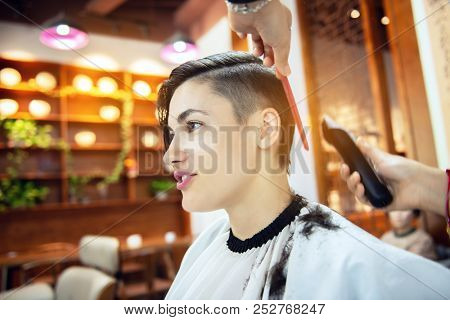 Beauty, hairstyle, treatment, hair care concept, young woman and hairdresser cutting hair at hairdressing salon. Hairdresser cuts beautiful girl's hair. Hairstylist serving client at barber shop. 