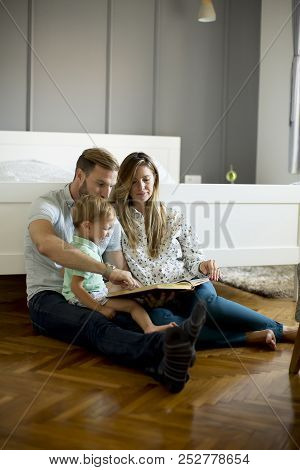 Parents Reading Book To Little Boy And Have Fun On The Floot In The Room