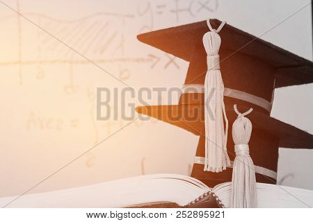 Education Graduate Two Mortarboard Hat On Textbook With Formula Equation Graph Or Mathematics On Scr