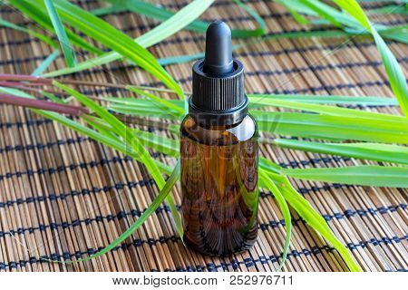 A Bottle Of Essential Oil With Fresh Lemon Grass On A Table