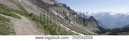 Panoramic View Of Alpine Mountains And Lush Vegetation In Summer With Snow Mountains In Background. 