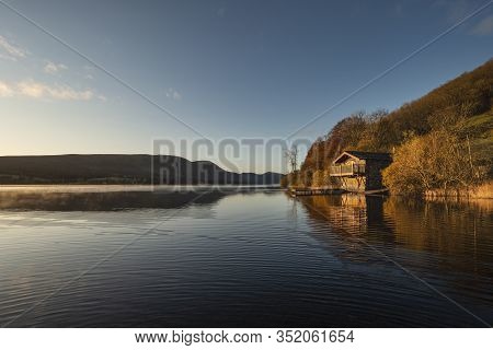 Stunning Sunrise Autumn Fall Landscape Image Of Ullswater In Lake District With Golden Sunlight