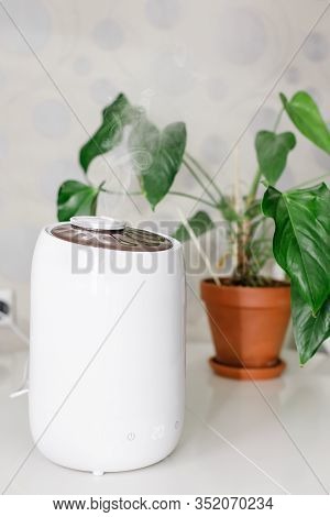 Vertical Photo Of White Air Humidifier Spreading Steam. Humidification Of Dry Air. Selective Focus O