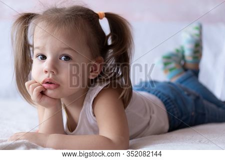Beautiful Girl Draws With Pencils In Bed. Little Girl Two Years Paints Coloring Book Lying On The Be
