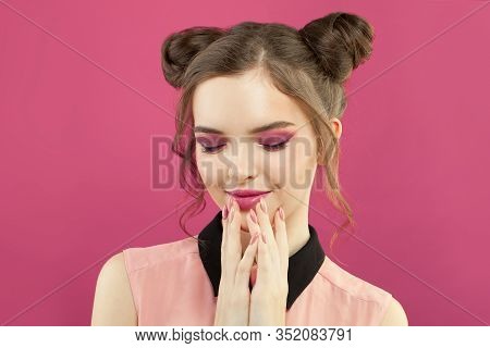 Pretty Model Woman With Fashion Makeup, Trendy Manicure Nails And Topknot Haircut On Bright Pink Bac