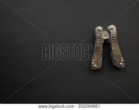 Multi Tool With Steel Handles On A Black Paper Background. Top View