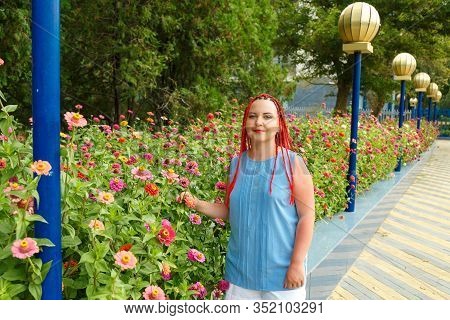 Young Woman With Red Hair Among Red Orange Colors.
