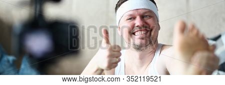 Cheerful Blogger Do Exercise And Hold Thumb Up. Happy Man Practice Stretching For Legs. Male Recordi