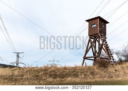 Power Poles Of A Power Line Next To A Hunter's Seat. High Seat For Animal Observation By The Foreste
