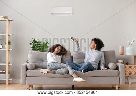 Happy African American Family Relaxing On Sofa Under Air Conditioner