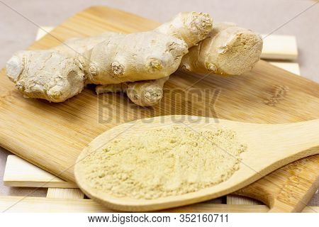 Fresh Raw Yellow Ginger Root With Ground Dry Powder In Wooden Spoon And On Wood Background.
