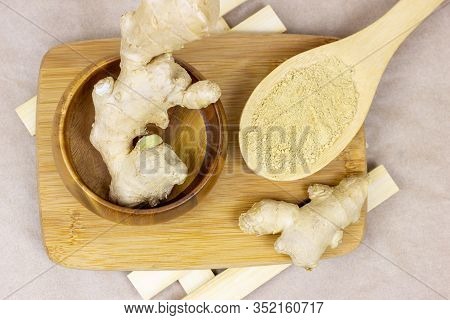 Fresh Raw Yellow Ginger Root With Ground Dry Powder In Wooden Spoon And On Wood Background.