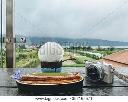Tabanan Bali, Indonesia - August 24, 2019: Churros, Hot Chocolote Drink And A Camera On The Table Wi