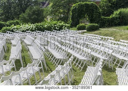 View Of The Rows Of White Wooden Chairs, Placed In A Semicircle, Without Spectators, Against The Bac