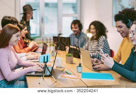 Happy young people working together inside office - Multiracial friends having fun in coworking space - Youth co-workers millennial generation and technology workspace concept