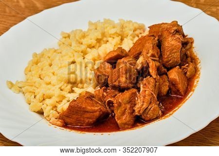 Tasty Hungarian Food Perkelt Sauce With Pork Meat And Tarhona On White Plate On Wooden Table